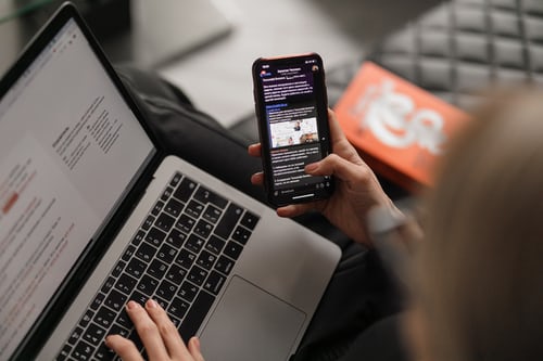 A person checking their emails on their laptop and holding their phone