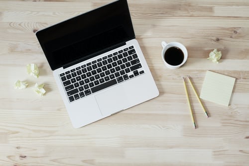 Notes, a laptop, and a coffee on a desk for a remote sales person