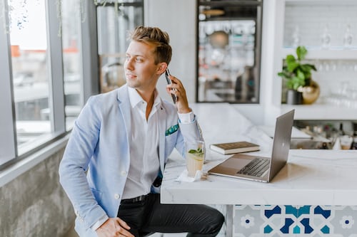 A salesman on a call sitting next to his laptop