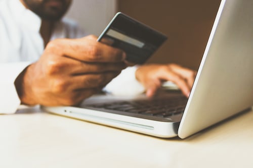 A man completing a transaction at his laptop holding his bank card