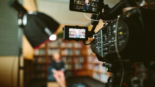 A TV camera filming an interview in a small study