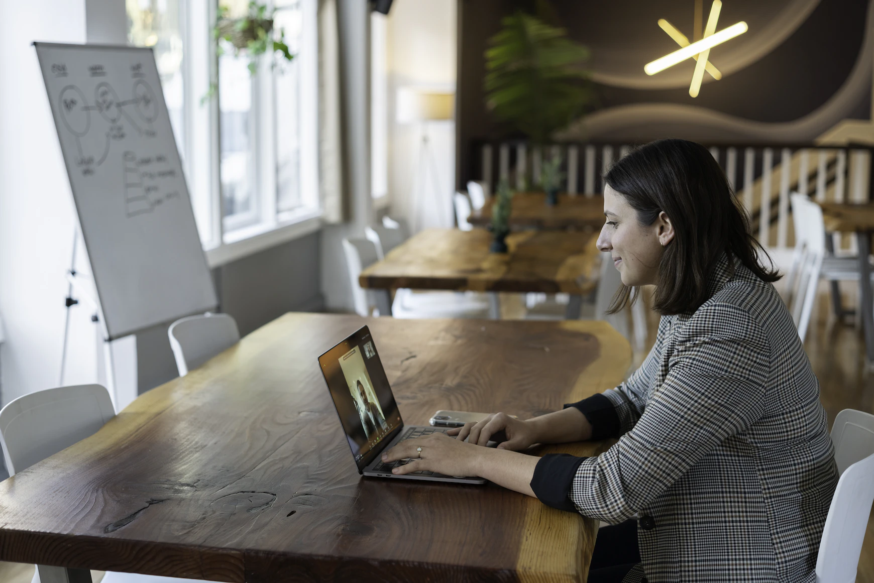 A salesperson having a virtual meeting at a brown desk with a laptop